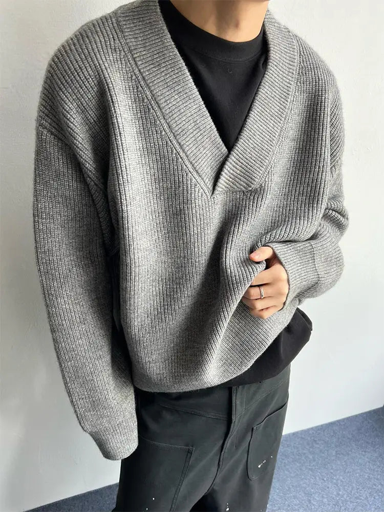 Gray ribbed knit relaxed v-neck pullover sweater worn over a black tee showcasing a layered look.