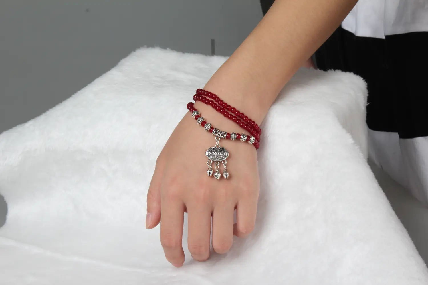 Red agate good luck bracelet featuring red beads with a silver-toned heart-shaped protect charm and smaller dangling hearts.