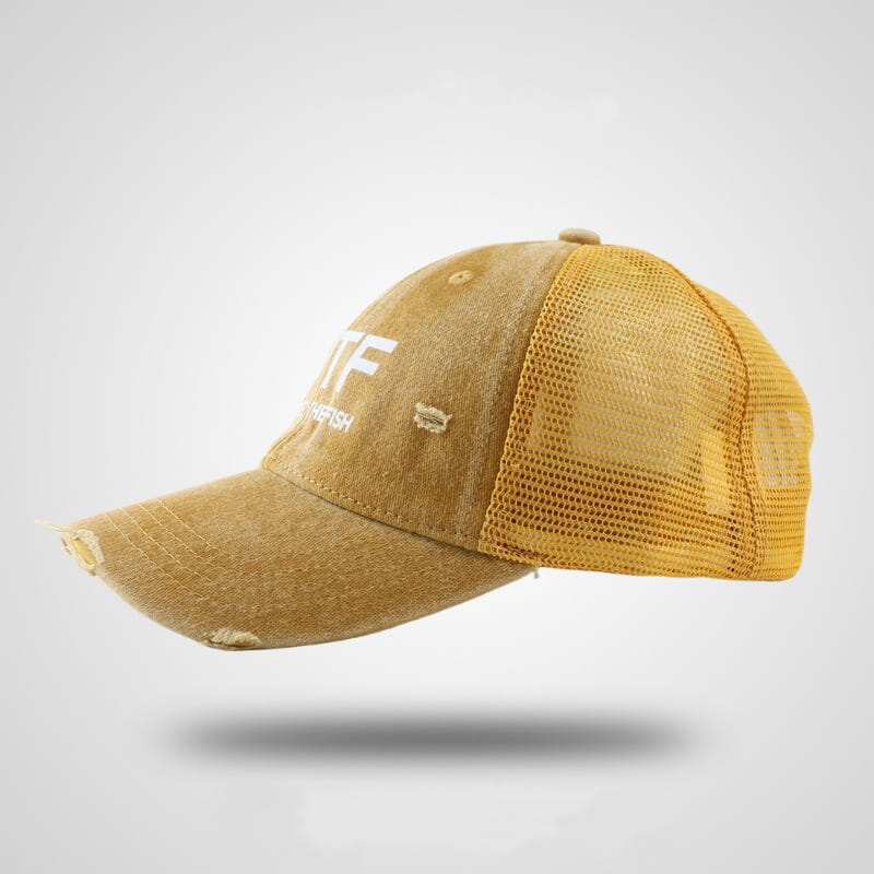 A distressed mustard-yellow fishing trucker hat with a mesh back and faded fabric featuring white embroidered lettering on the front.