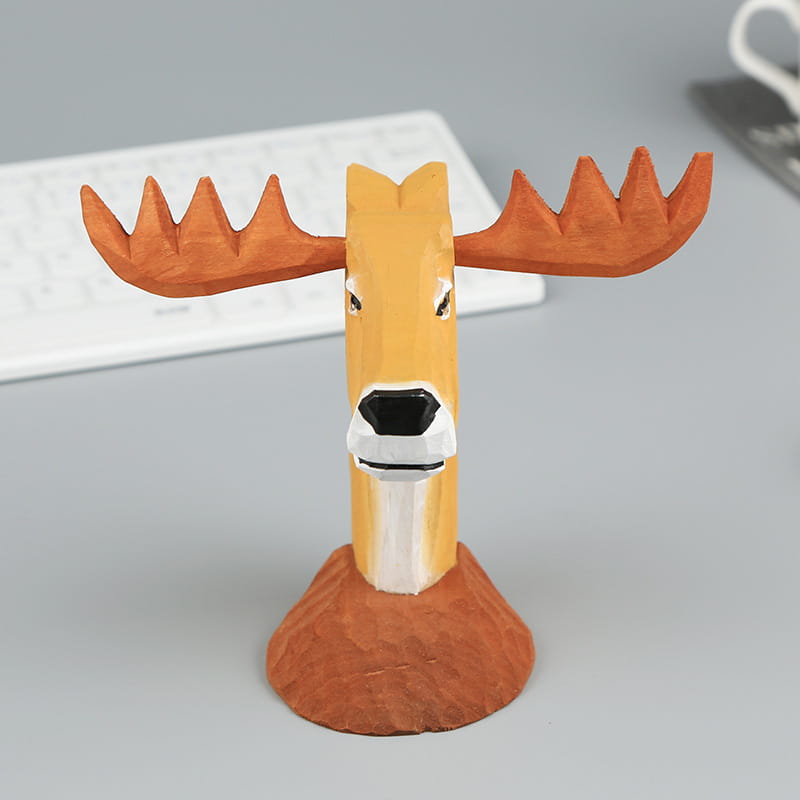 Figurita tallada a mano en madera con la cabeza de un alce con astas naranjas, rostro color beige, hocico blanco y nariz negra, sobre una base marrón, que sirve como soporte creativo para gafas para la decoración del hogar.