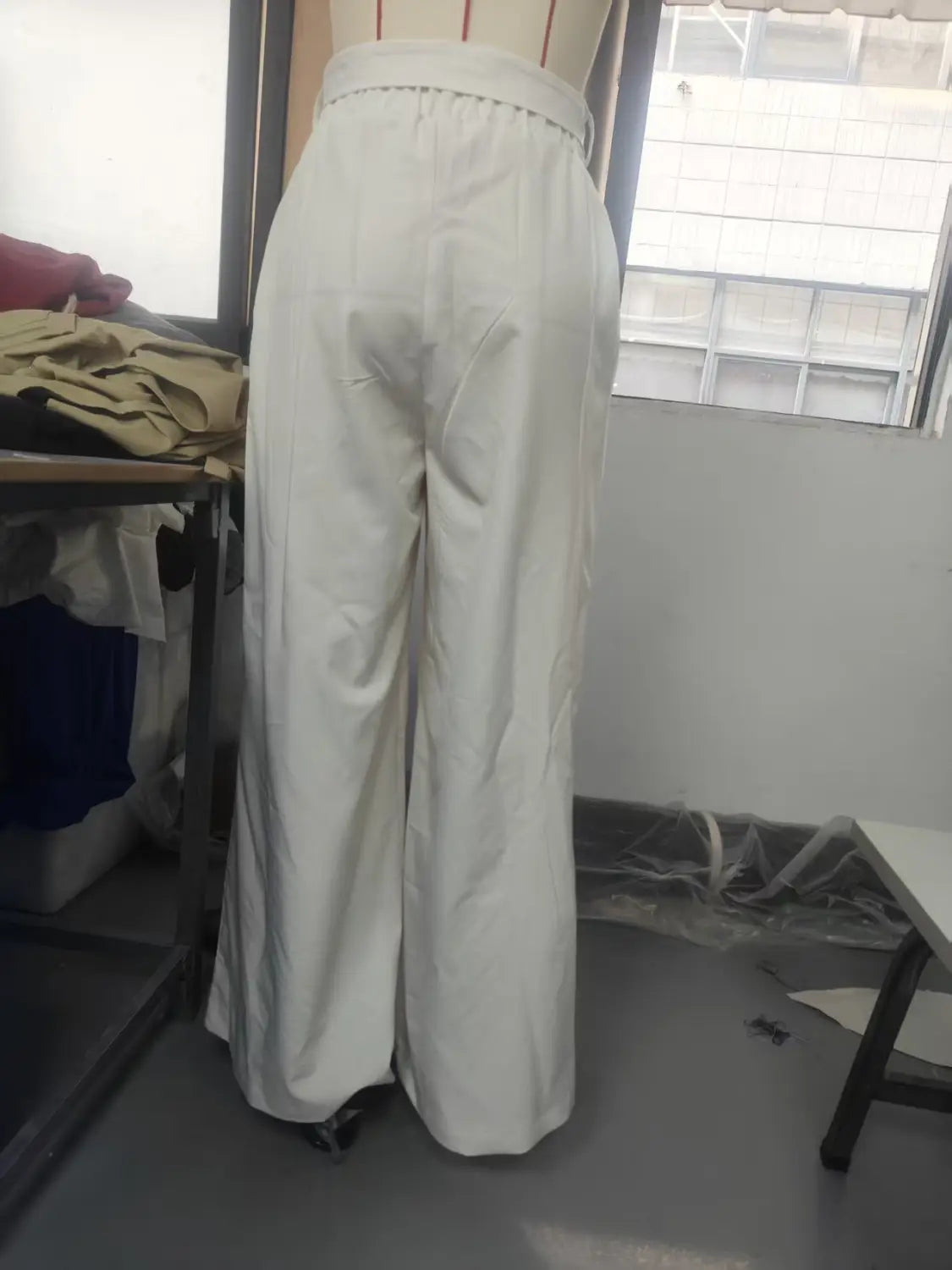 Pantalon ample décontracté blanc à taille haute, avec de subtils plis à l’arrière, visible de la vue arrière.