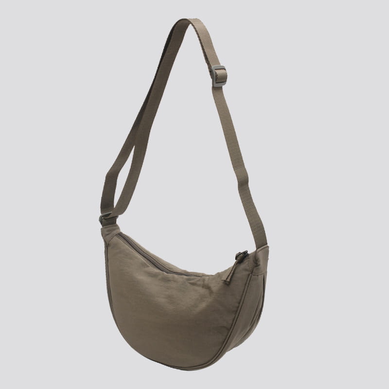 A sleek olive-green nylon dumpling messenger bag with a minimalist design and a curved adjustable crossbody strap.