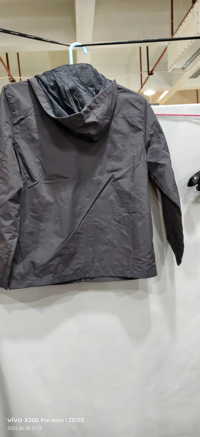 Chaqueta de senderismo con capucha impermeable color gris oscuro, confeccionada con tejido resistente al agua, con un sutil detalle de costuras.