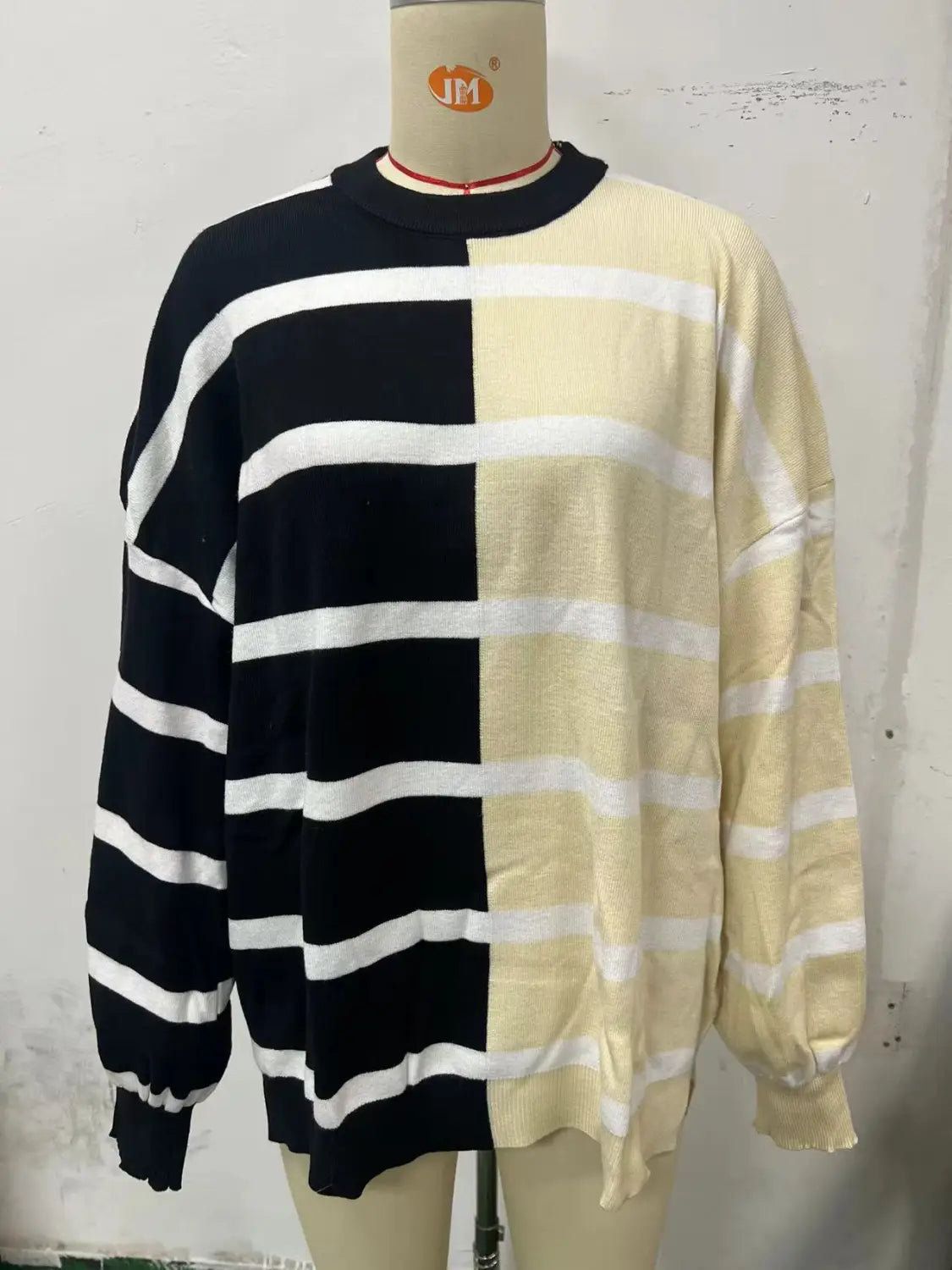 Black and cream-colored striped knit sweater with a split front design, long sleeves, and ribbed cuffs for a women’s oversized fit.