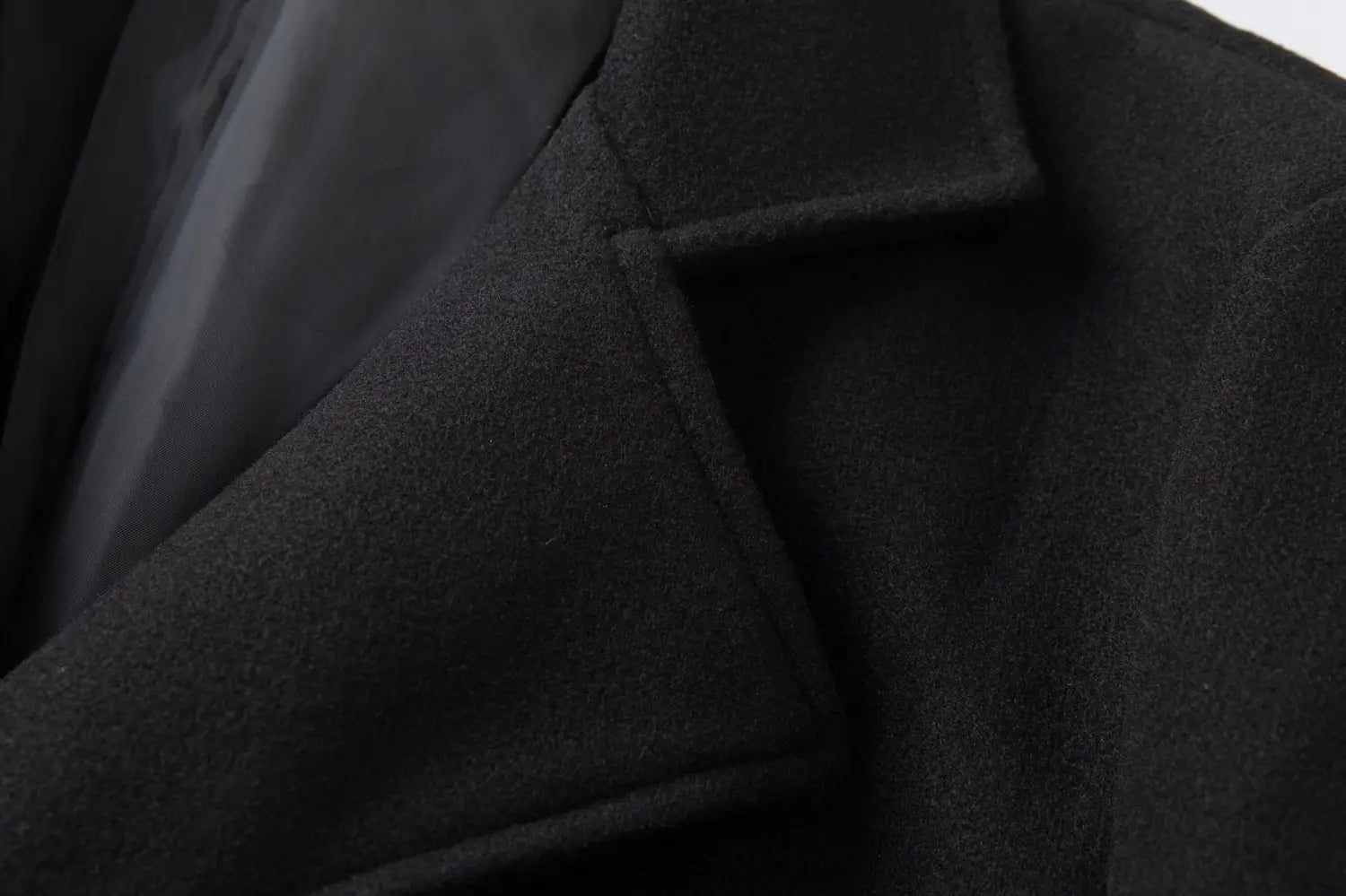 Black double breasted wool overcoat with mid length fit and a structured collar featuring subtle texture.