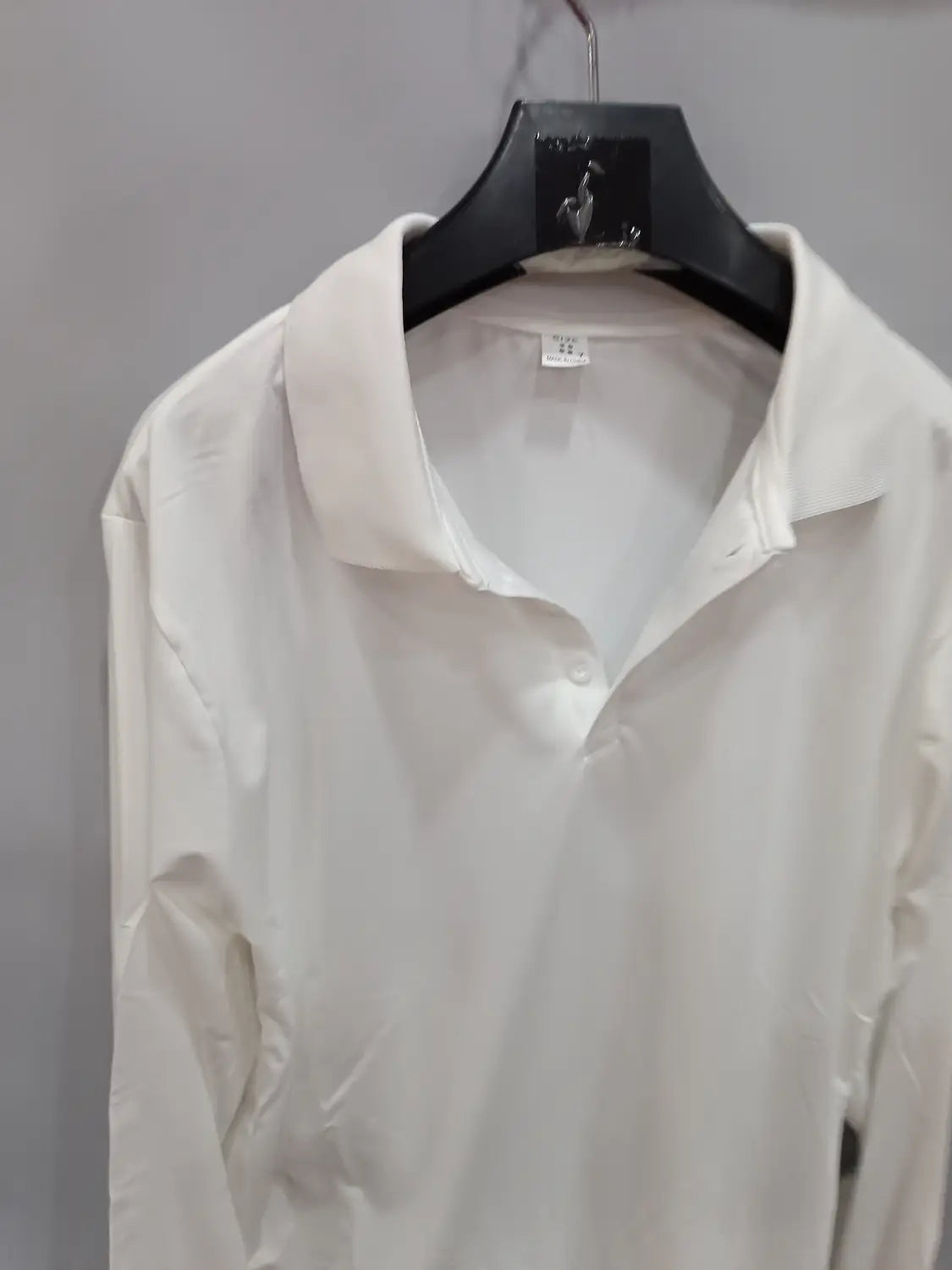 Ein frisches weißes langärmliges Polohemd mit klassischem Kragen, ordentlich an einem schwarzen Kleiderbügel hängend, geeignet für Casual-Sportbekleidung.
