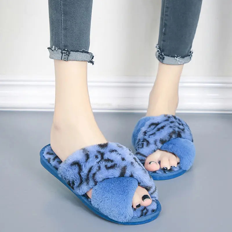 Blue fuzzy slip-on slippers with a leopard print cross strap upper made of plush material for indoor use.
