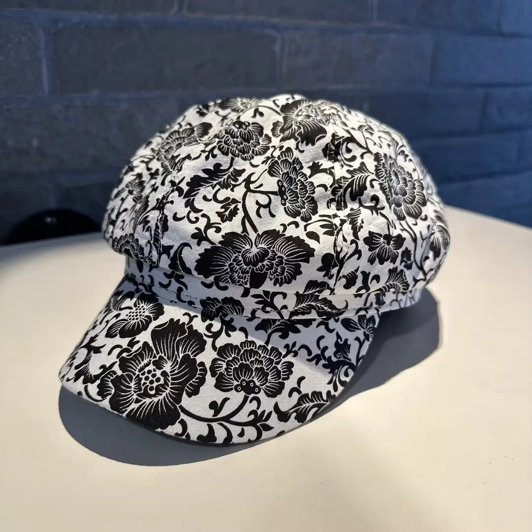 A black and white floral-patterned fabric newsboy cap for women.