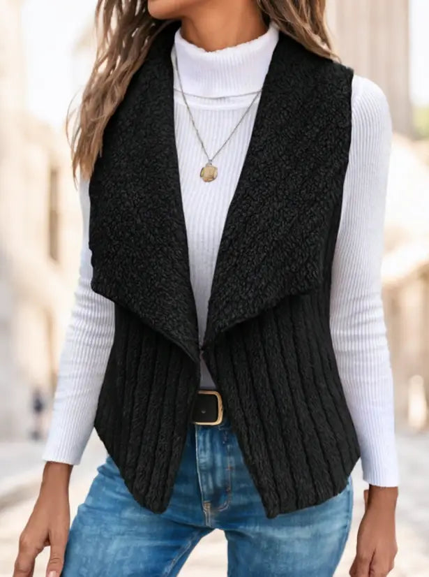Schwarze gerippte Strickweste mit Wasserfallkragen, drapiertem Vorderteil und goldfarbenem Gürtelschnallenverschluss in der Taille.