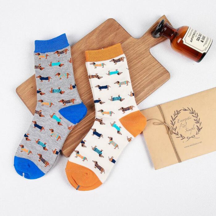 Gray and white cotton crew socks featuring playful dachshund patterns with blue and orange accents in the cute dog cartoon design.