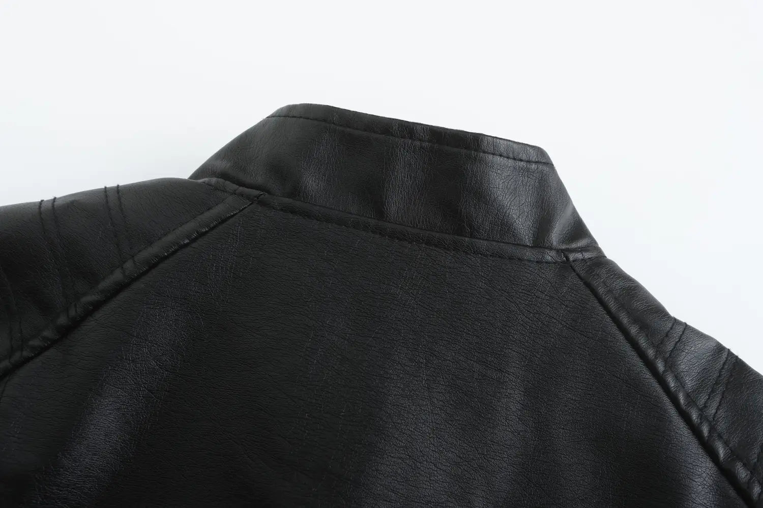 Veste motard en faux cuir noire avec col montant, avec coutures apparentes et surface lisse légèrement texturée.