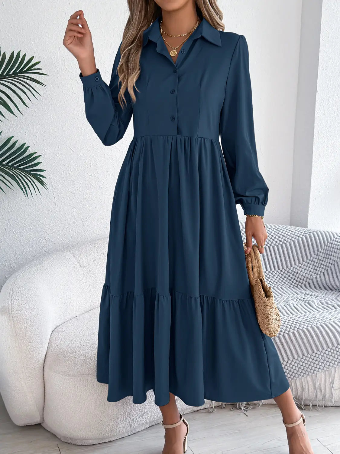 A navy blue long sleeve button down midi dress with a tiered skirt and gathered waist made from lightweight fabric.