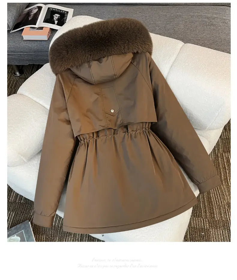 Manteau matelassé marron, capuche doublée de fourrure marron foncé duveteuse et taille resserrée, conçu comme une parka matelassée à capuche avec col de fourrure.