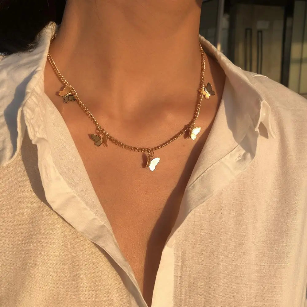 Elegant butterfly charm choker necklace in gold and silver featuring a gold chain adorned with delicate butterfly charms in varying shades of gold and white.