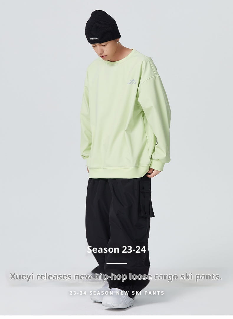 light green oversized sweatshirt with a small embroidered logo on the left chest paired with winter outdoor loose ski pants designed for cold weather activities.