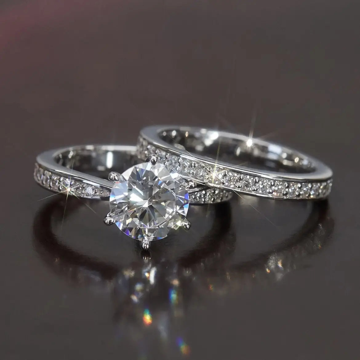 A round cut zircon wedding ring set in white gold finish featuring a sparkling engagement ring with a central round-cut stone and pavé-set diamonds along the band paired with a matching wedding band.