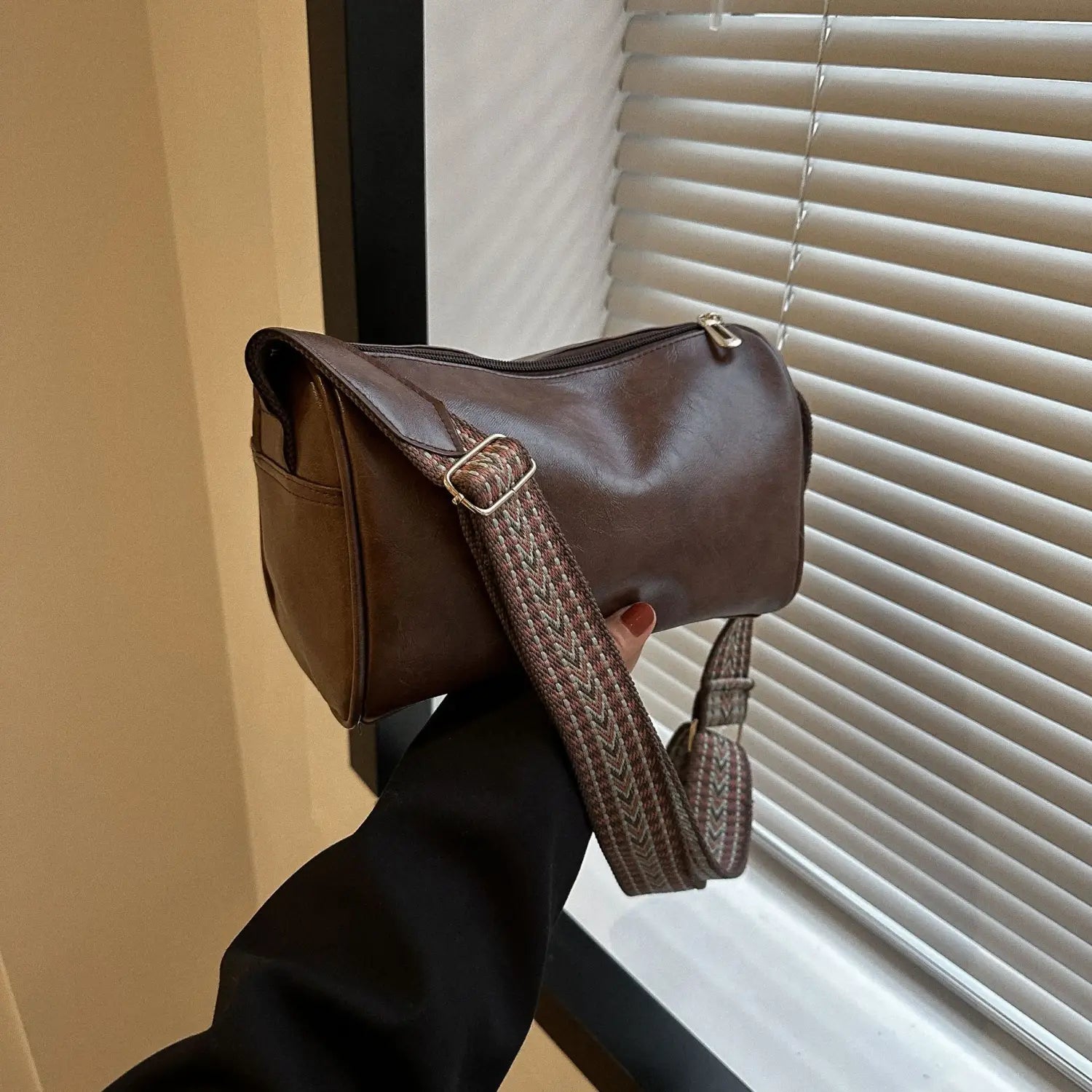 Retro leather crossbody bag in brown with a woven patterned strap and gold tone hardware.