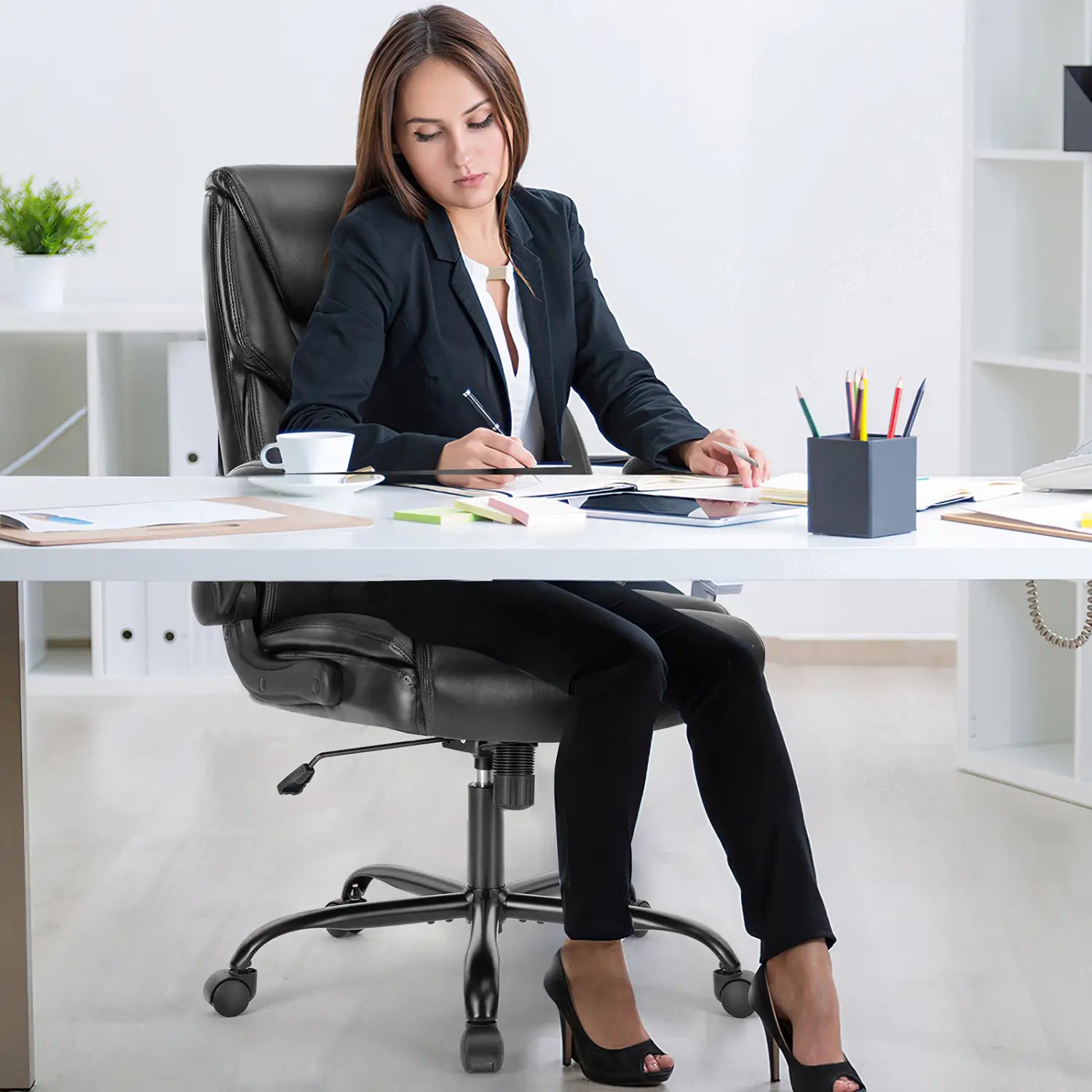 Silla de oficina ergonómica de cuero negro con brazos abatibles y base de cinco ruedas, mostrada desde el lado posterior.