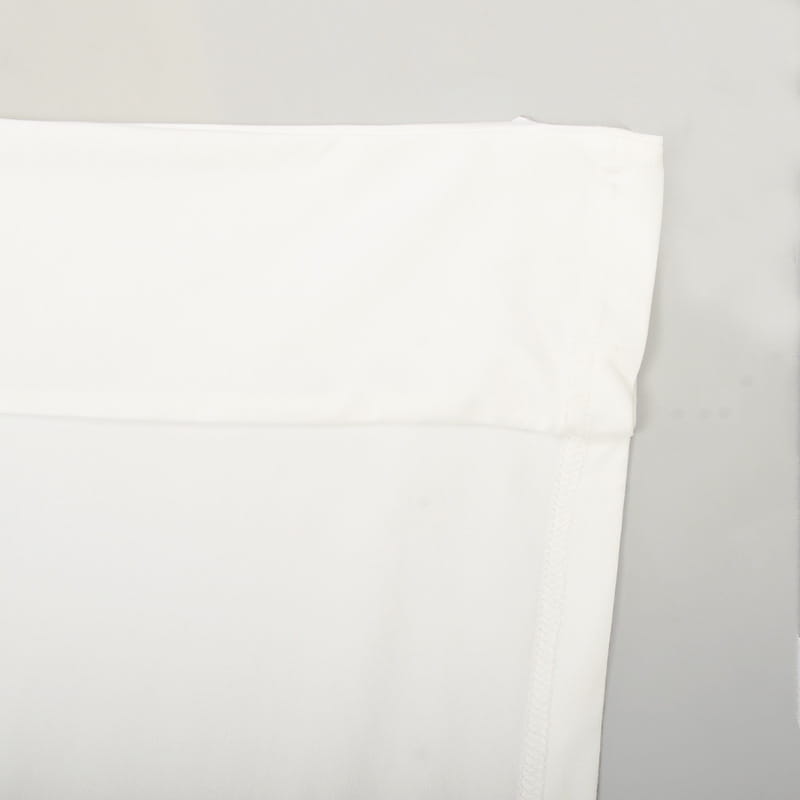 white cotton pillowcase with a neatly folded edge displayed alongside an asymmetrical satin batwing sleeve maxi dress.