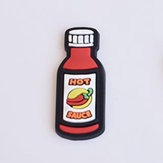 food themed shoe charm in the shape of a red hot sauce bottle with black outline and white cap designed for sandals and clogs.