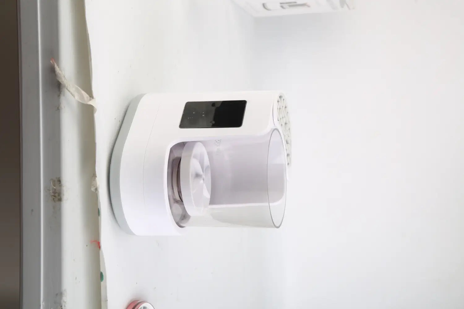 white wall-mounted electric makeup brush cleaner uv sterilizer and dryer with a transparent cylindrical filter housing and a digital display panel