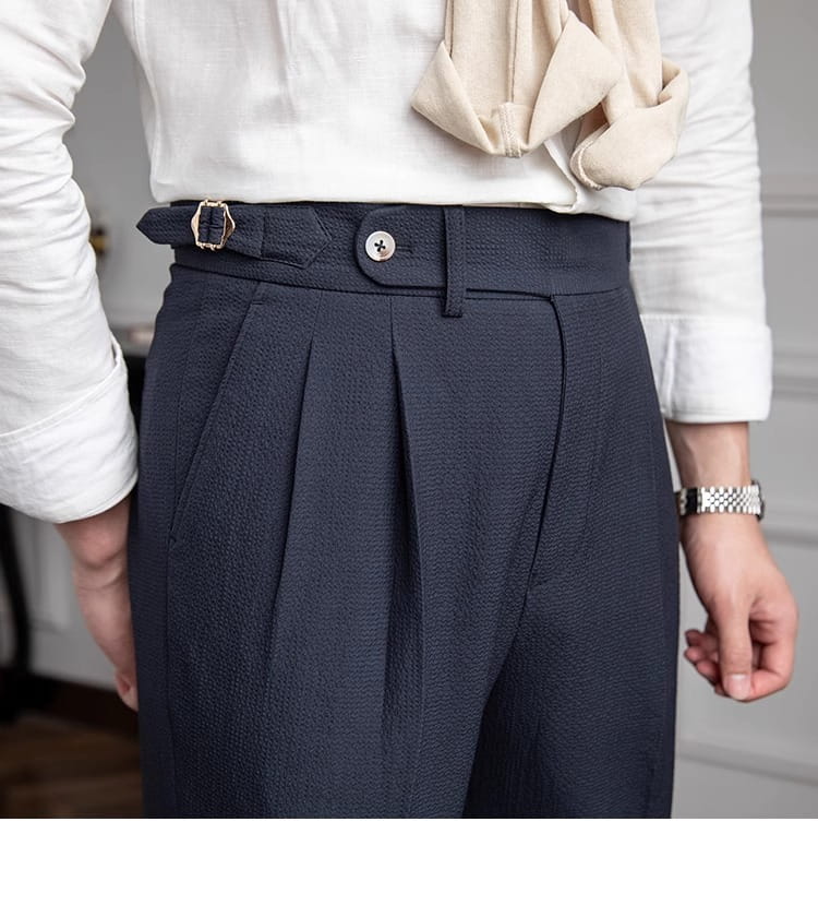 Men’s slim fit pleated summer linen suit trousers in dark navy with textured fabric and a metallic buckle at the waistband.