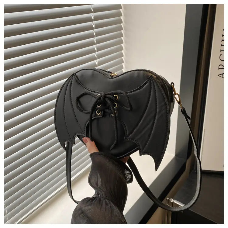 Black bat-shaped crossbody bag featuring lace-up front and gold-tone hardware in a gothic style design.