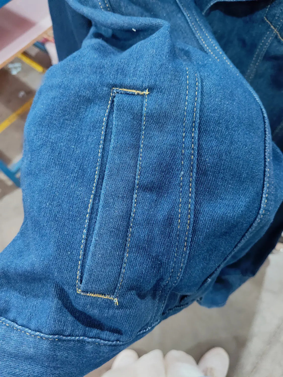 men light wash slim fit denim jacket in blue with a visible patch pocket stitched in contrasting yellow thread