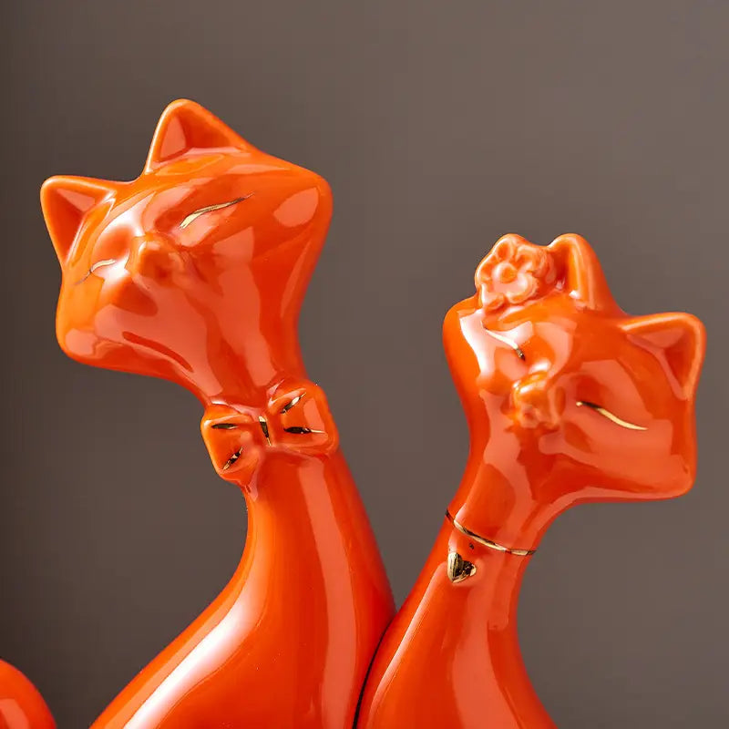 Vibrant orange ceramic cat figurines with glossy finish and gold accents for modern gold and white home decor.