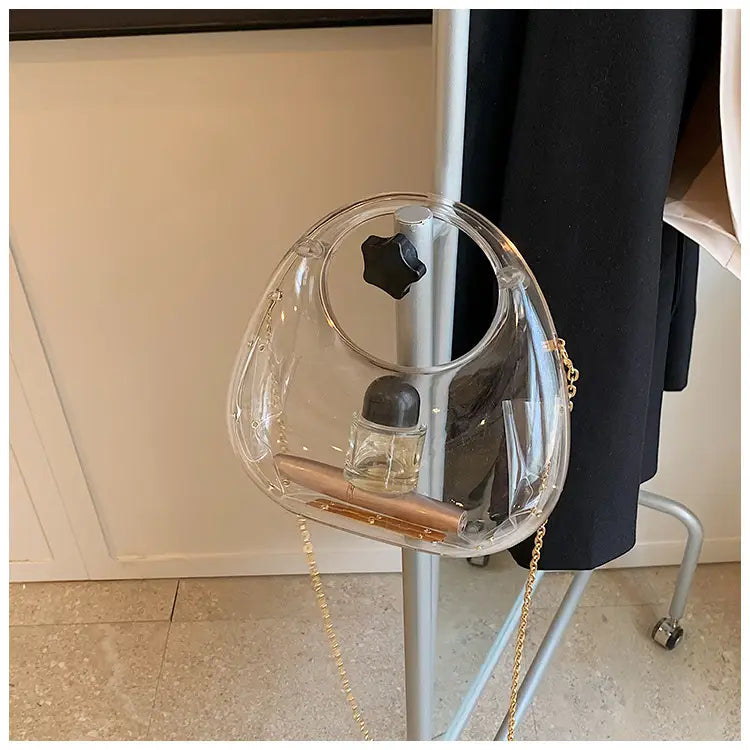Clear plastic acrylic egg-shaped handbag with gold chain strap and black star-shaped clasp metallic clutch bag.