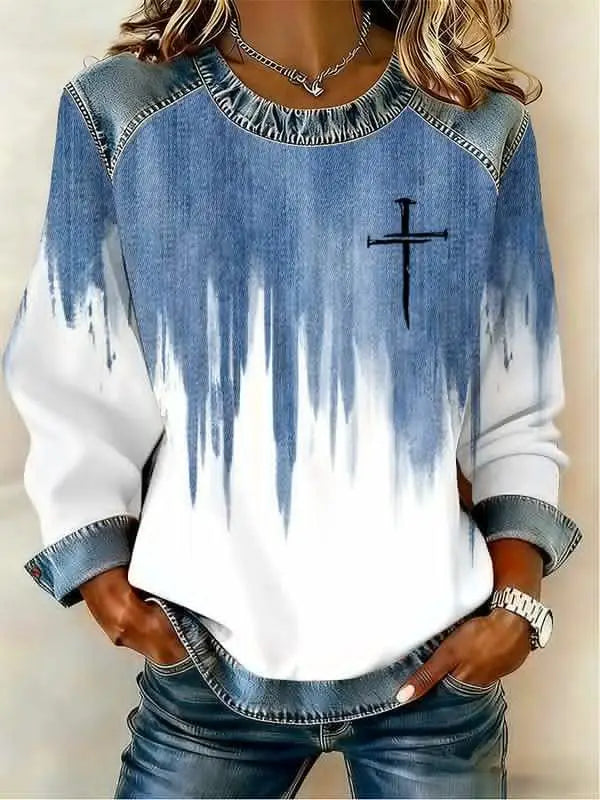 Sweat-shirt manches longues en denim et en dégradé blanc avec un graphique croisé noir sur la poitrine et des accents en denim à paillettes rouges.