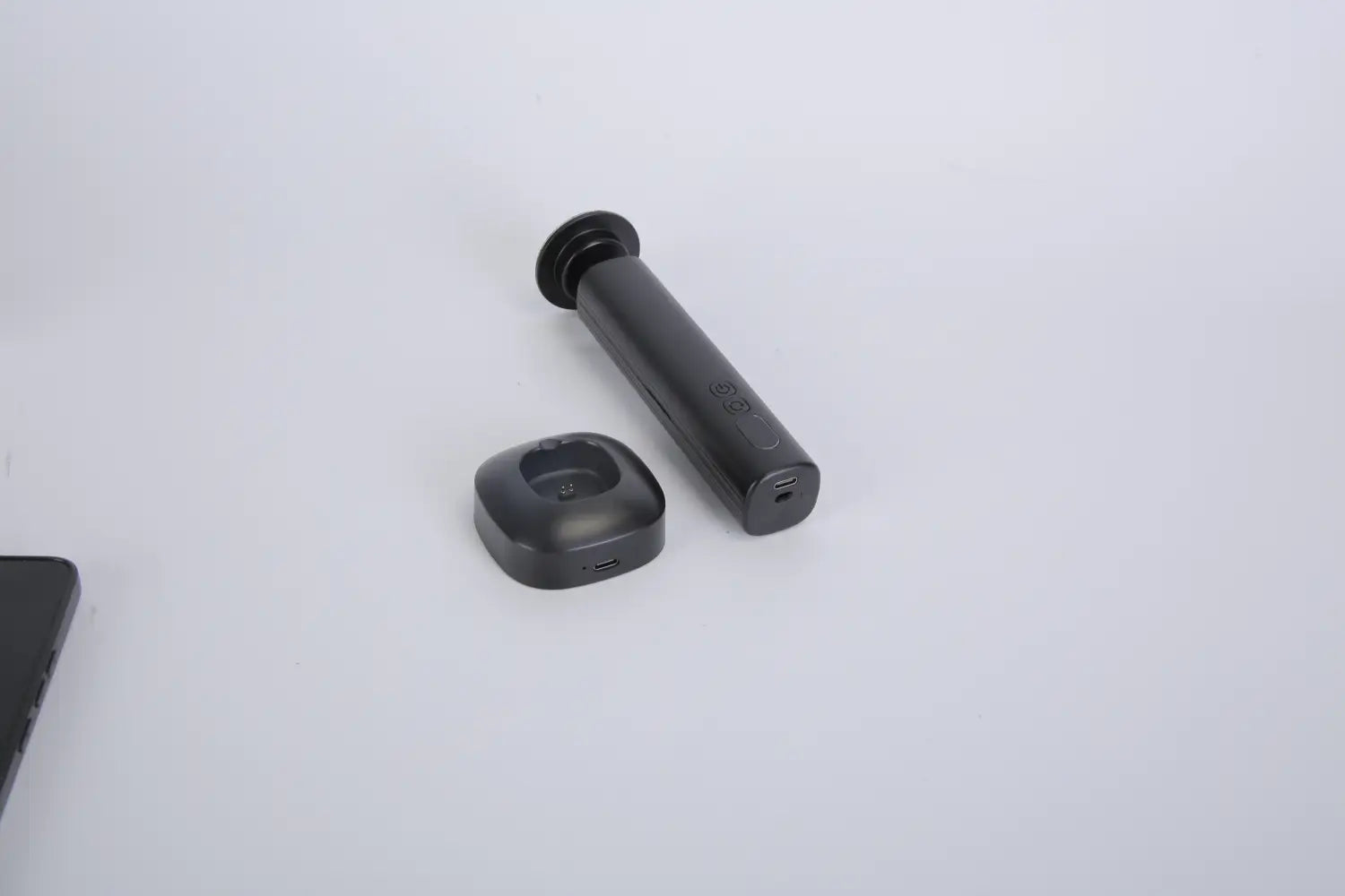black cylindrical wireless earbud with circular charging case shown alongside electric foot callus remover and nail grinder kit for personal grooming