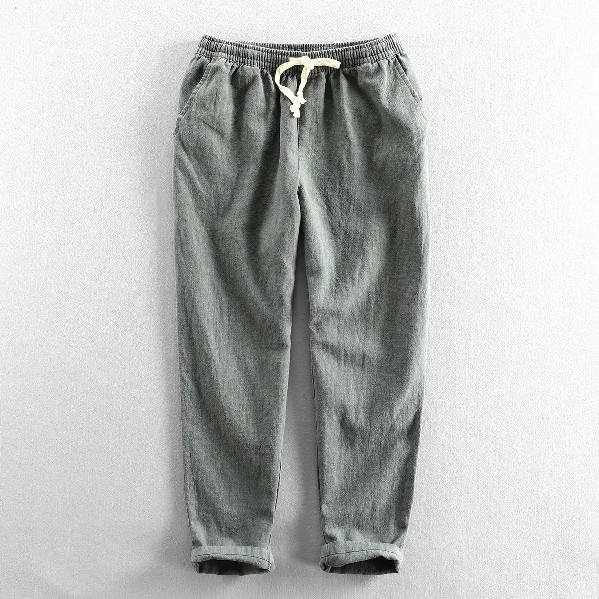 Men’s relaxed fit drawstring linen joggers in gray with a white waistband and rolled cuffs.