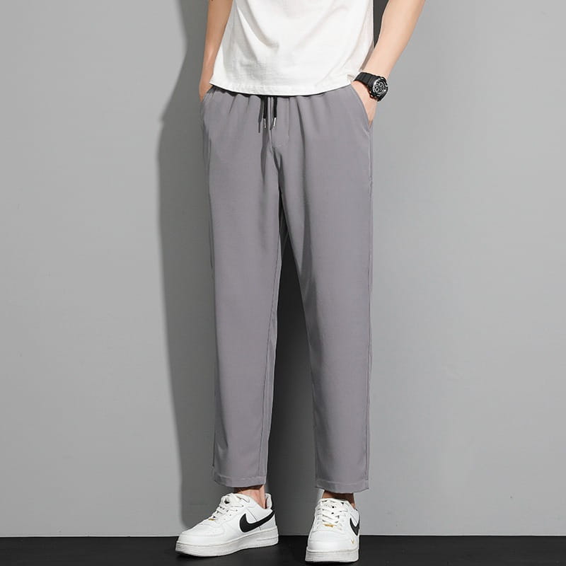 Graue, schmal geschnittene Baumwoll-Joggerhose für Herren mit Kordelzugbund und zulaufenden Beinen, Herren-Freizeithose mit Kordelzug.
