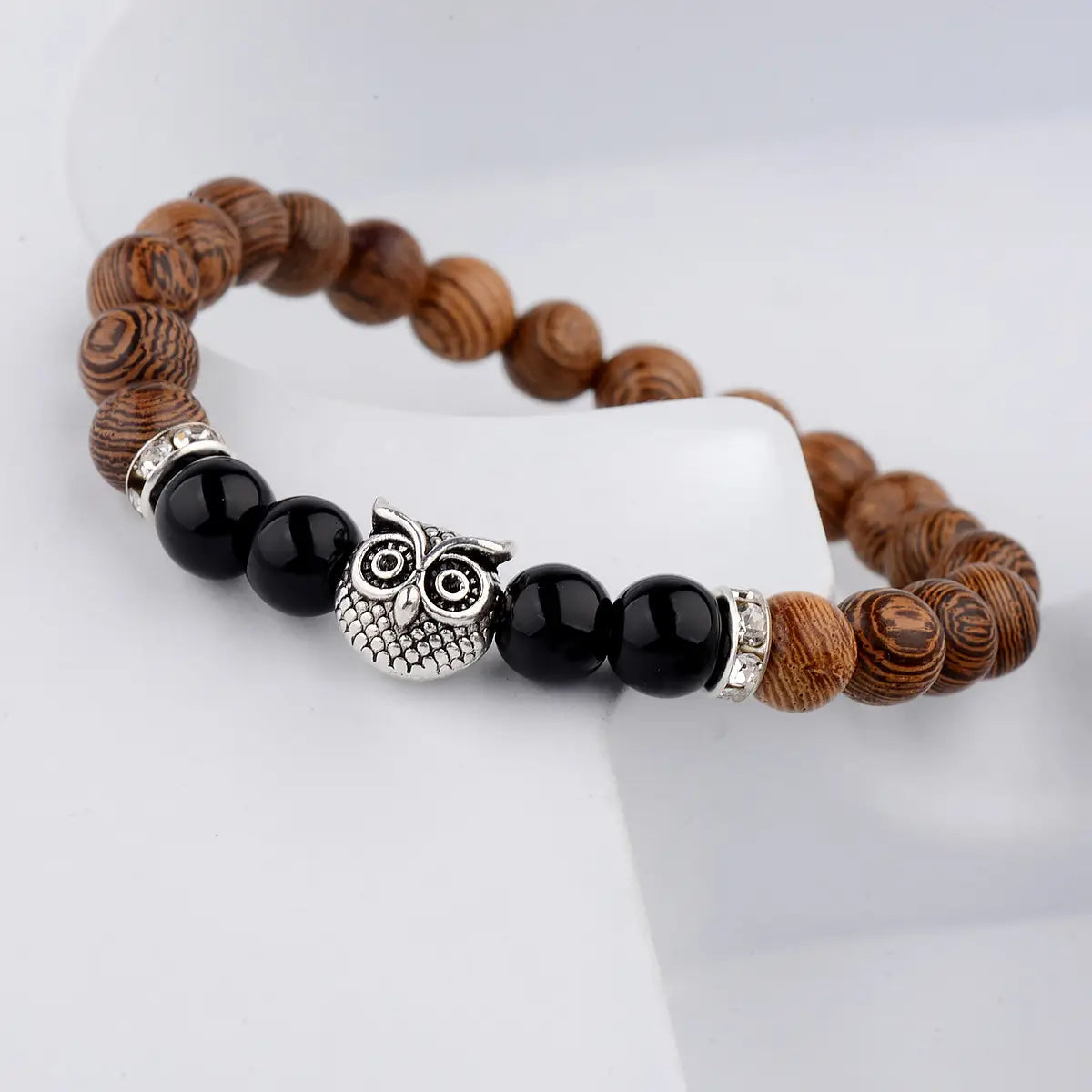 A brown wood-patterned beaded bracelet featuring black onyx beads and a silver owl charm in the crystal owl charm wood and onyx beaded bracelet collection.