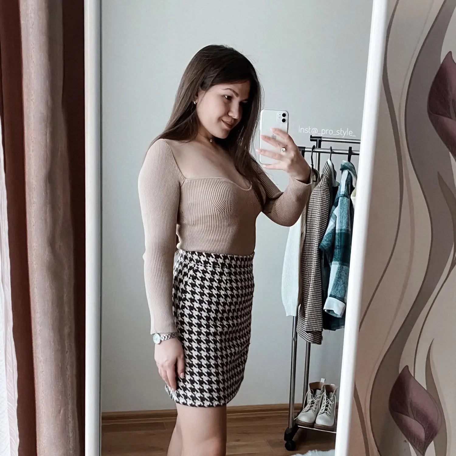 A woman wearing a beige ribbed sweetheart neck long sleeve knit pullover paired with a black-and-white houndstooth pencil skirt.