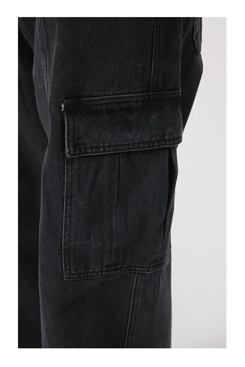 Black denim cargo pants with a rugged distressed texture and reinforced stitching in a retro loose fit wide leg style.