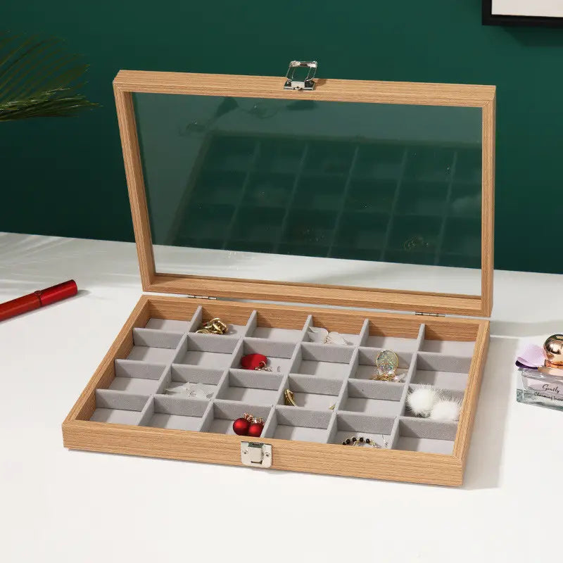 Rosewood jewelry display box with a light wood finish, glass lid, silver-toned latches, and gray felt-lined compartments for organized storage.