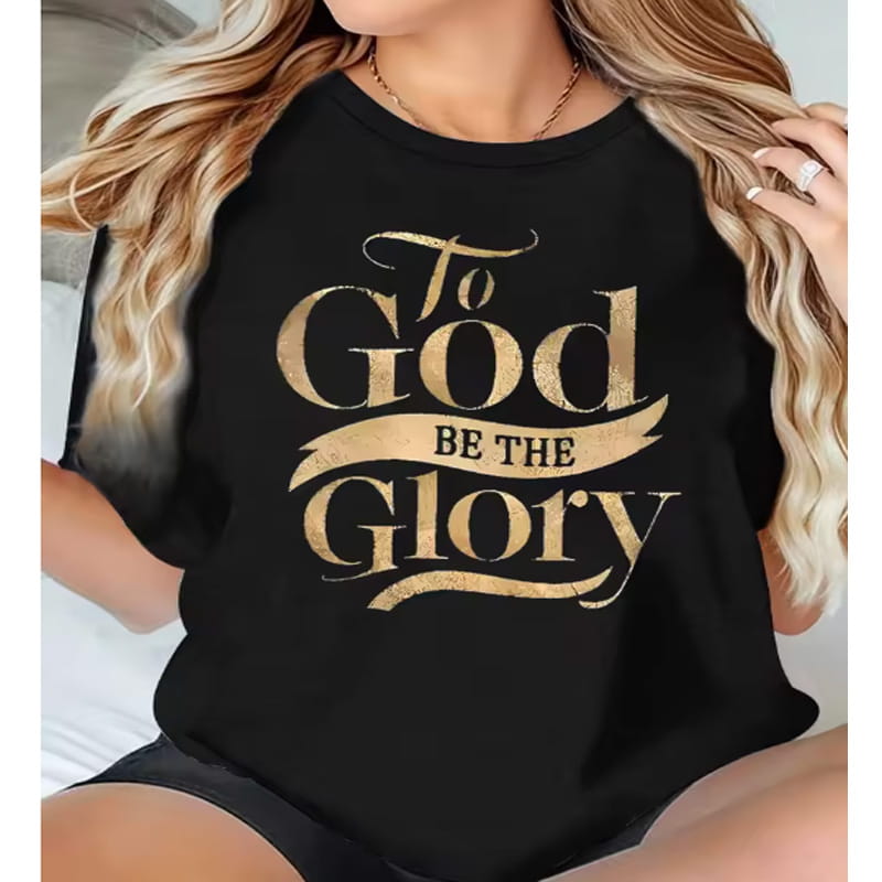 Camiseta negra de manga corta de algodón con letras en pan de oro que dicen «To God be the Glory» en una tipografía decorativa tipo caligrafía.