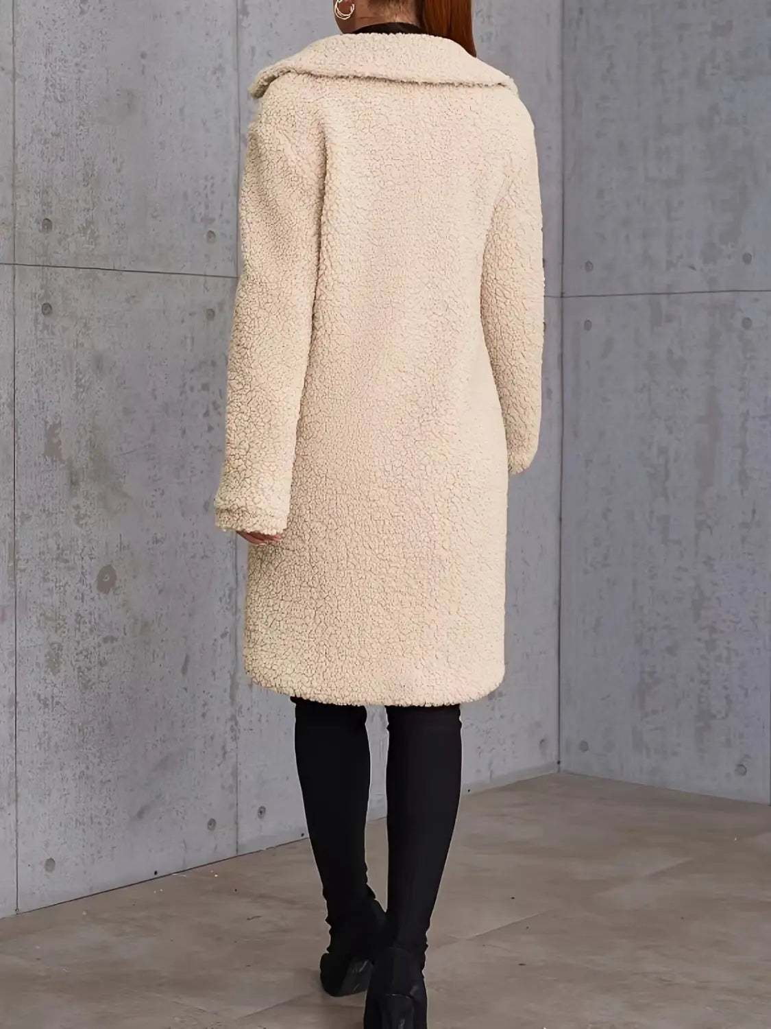 Manteau teddy mi-long doublé en polaire de couleur crème, confectionné dans une fausse fourrure moelleuse, avec un col douillet et des manches longues.