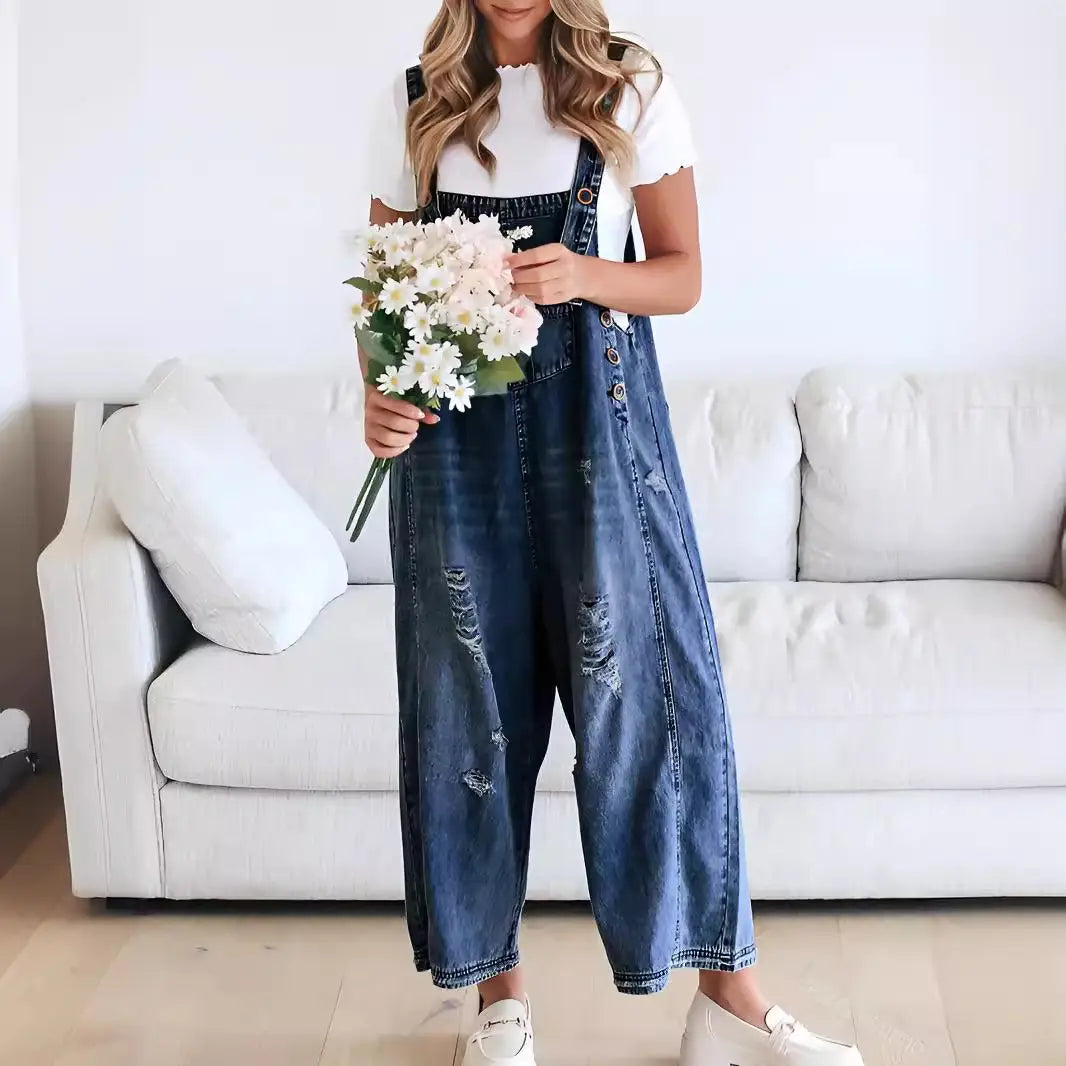 women’s dark blue denim overalls with distressed patches, adjustable straps, and button closures made from durable denim material.