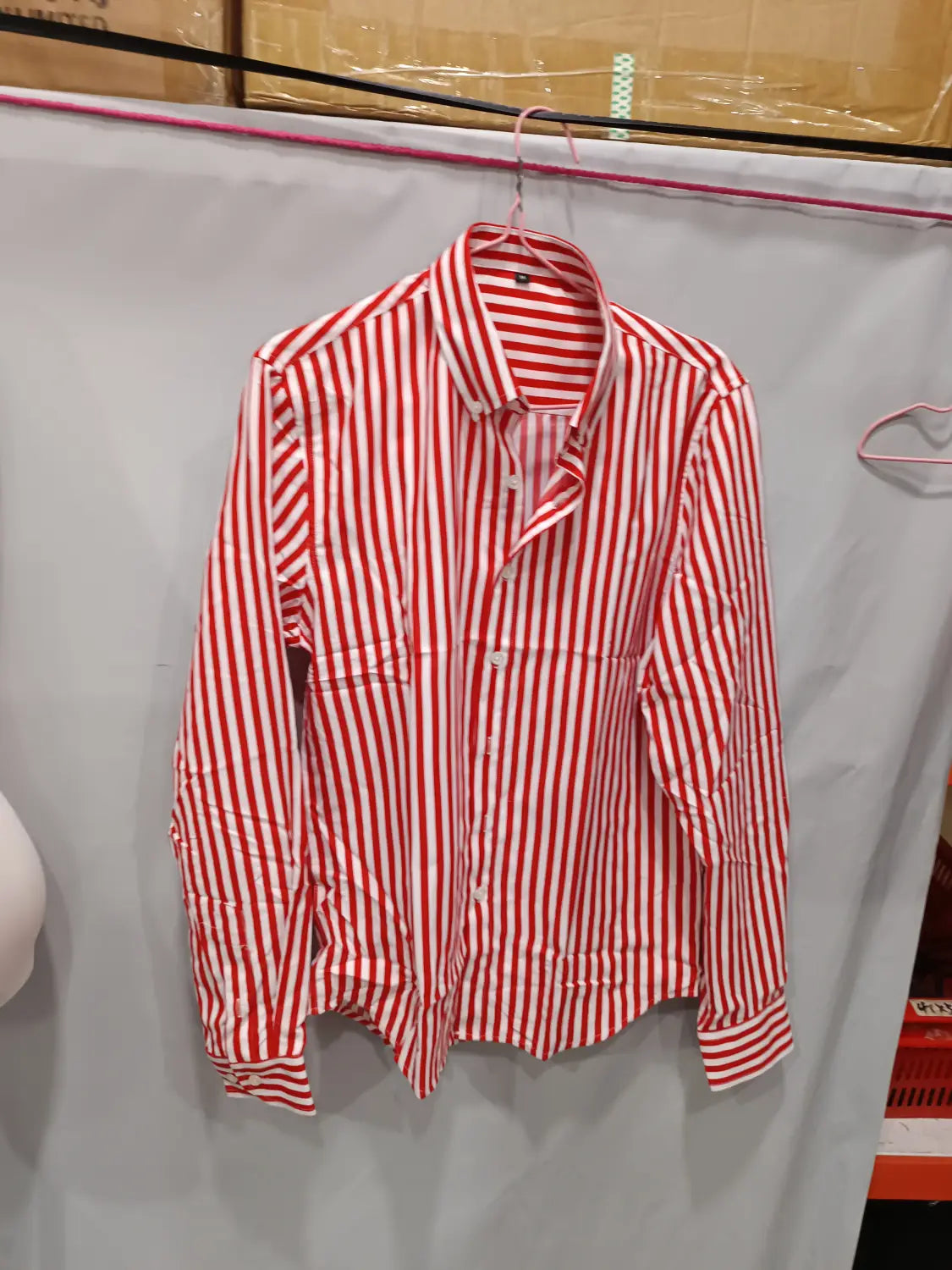 Herren gestreiftes Slim-Fit-Langarm-Freizeithemd in rot-weißen vertikalen Streifen, das an einem rosa Bügel hängt