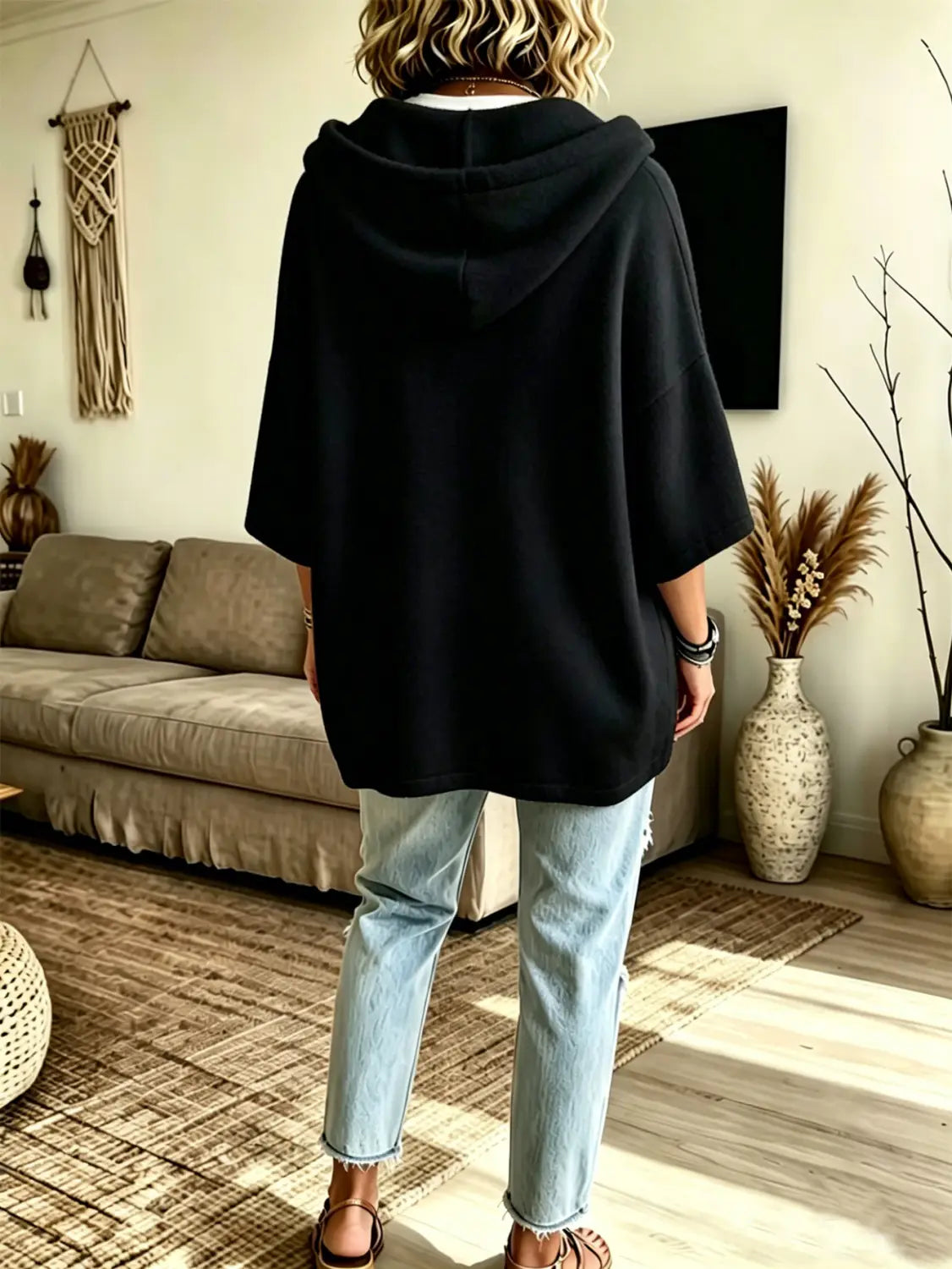 Black oversized fleece hooded top with three-quarter sleeves and a relaxed fit displayed from the back side.