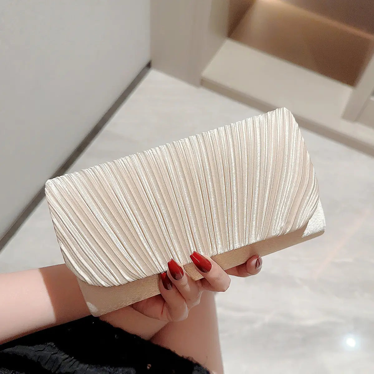 A sleek off-white minimalist women’s evening bag clutch with a pleated satin finish and a contrasting beige base.