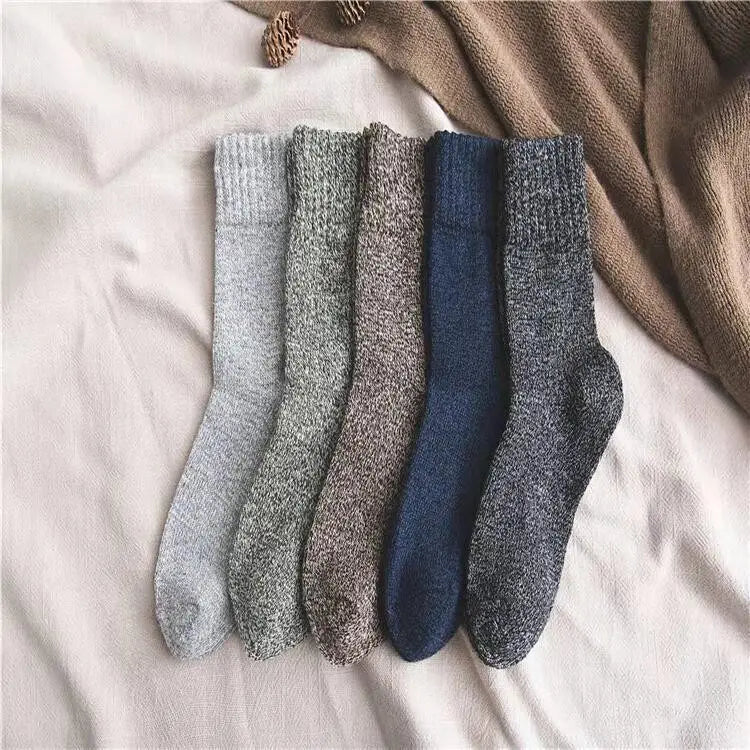 five cozy men’s rabbit fur winter socks in muted gray beige navy blue and dark charcoal hues arranged on a soft white fabric surface showcasing textured knit material.
