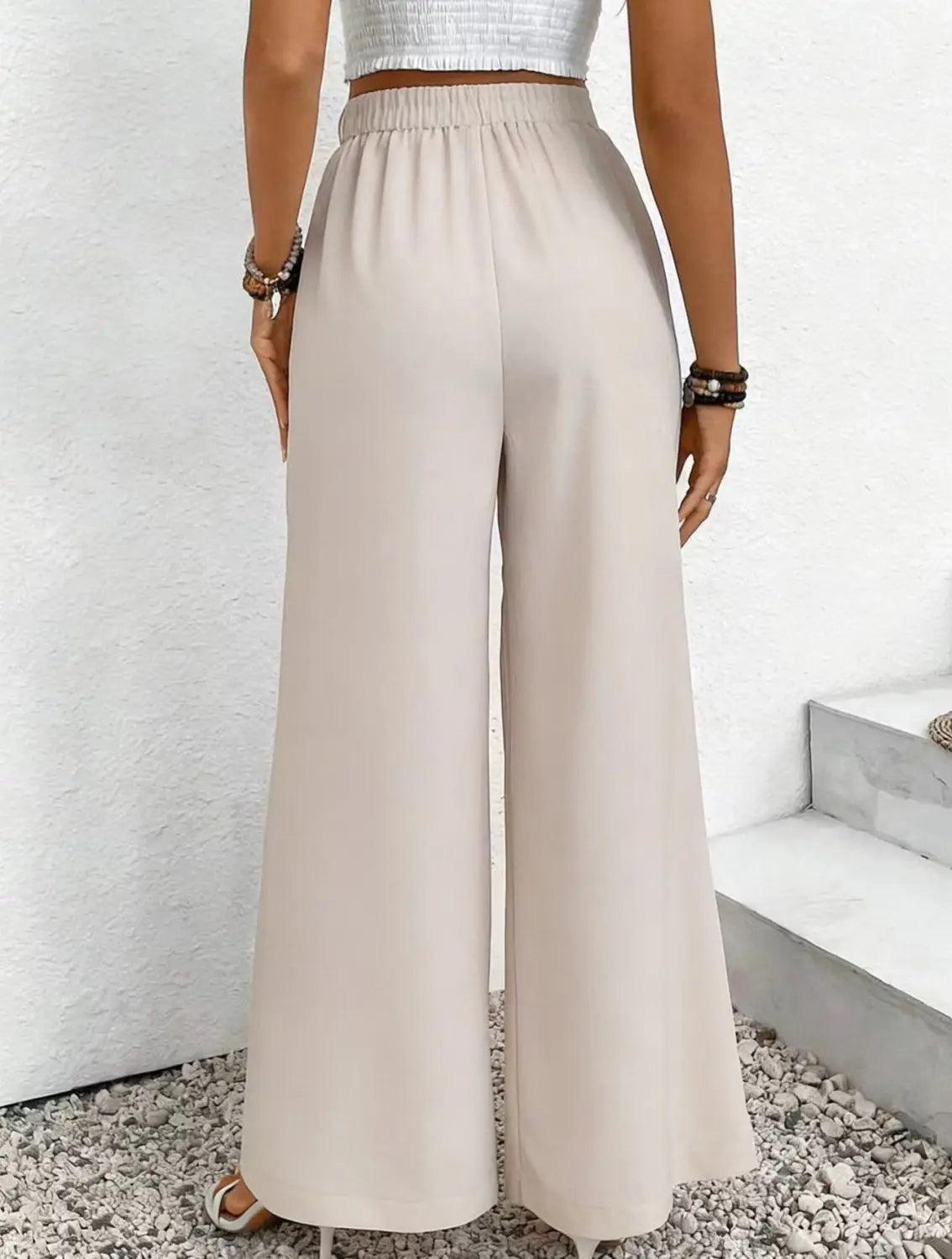 Pantalon ample à taille haute beige, en tissu fluide lisse, avec une taille élastique.