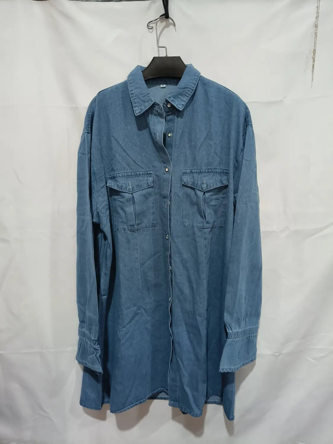 Blaues Jeansstoff-Kleid im A-Linien-Schnitt, mit weitem Langarm, mit Knopfverschluss vorn, zwei Taschen und elastischen Bündchen.