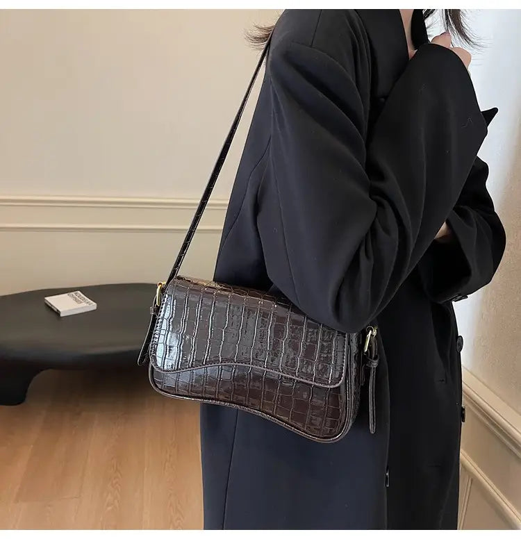 Dark brown crocodile-embossed leather messenger bag with a minimalist structured design and matching crossbody strap.