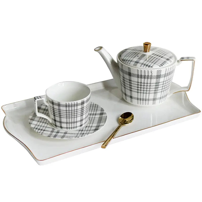 White ceramic teapot with black and gray plaid pattern and gold-trimmed lid knob and handle from a ceramic tea set with plaid teapot and gold trim tray.