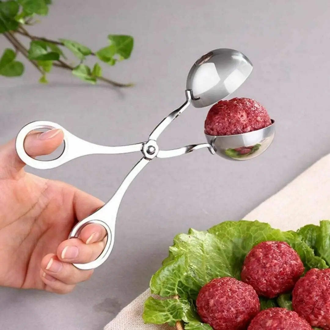 Stainless steel meatball maker tongs with two spherical reflective bowls and ergonomic handles for kitchen use.